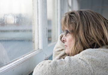 Lady wearing glasses stares out a window